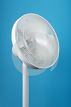 A high-tech white electric fan with a modern design for cooling the room on a blue background