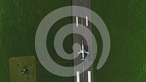 High top view of private aircraft moving along take off in countryside`s runway among grass lawns. 4K.