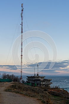 High tower. Telecommunications antenna on the high sea shore. Early autumn morning. Mainly cloudy