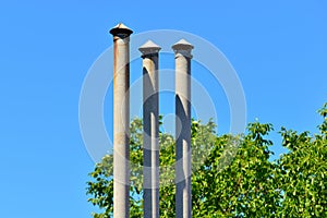 High triple chimney at the house next to the green trees