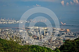 High view angle picture of Kobe cityscape crowded with houses and buildings with seashore and oil refinery industry