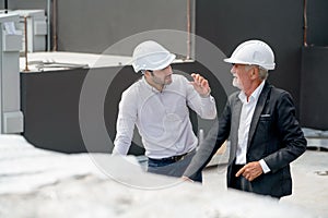 High view of two engineer or technician workers discuss together on rooftop of constuction site photo