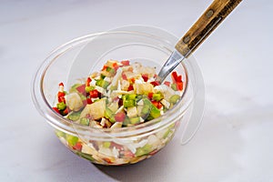 High view of a typical bell pepper and onion vinaigrette with vinegar and olive oil in a transparent bowl. Healthy and natural photo
