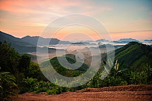 High views with views of mountains and fog interspersed among lush green forests at sunrise, golden light, sky and colorful clouds