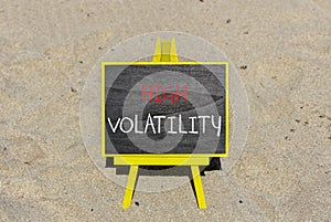 High volatility symbol. Concept words High volatility on beautiful black chalk blackboard. Chalkboard. Beautiful sand background.