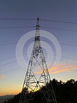 High voltage cable tower during sunset on a mountain