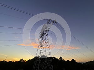 High voltage cable tower during sunset on a mountain