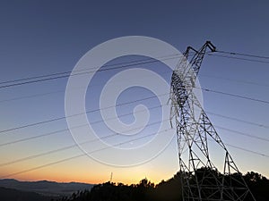 High voltage cable tower during sunset on a mountain