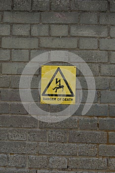 High voltage danger yellow sign on a brick wall