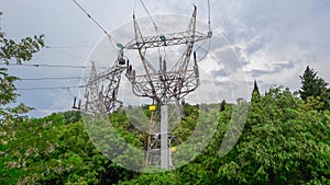 High voltage elecricity pylons come outside a green forest