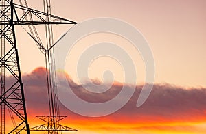 High voltage electric pole and transmission lines. Electricity pylons at sunset with orange sky. Power and energy. Energy