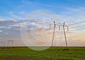 High voltage electric poles, rural landscape with power pylons in a row, at sunset