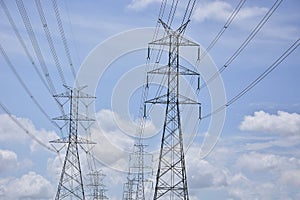 High voltage electric power lines on pylons in blue sky