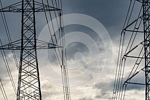 High voltage electric pylon and electrical wire against stormy sky and clouds. Bottom view of electric pylon. High voltage grid