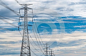 High voltage electric pylon and electrical wire with blue sky and white clouds. Tall electricity pole. Power and energy concept.