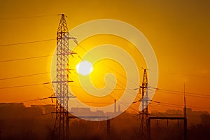 High-voltage electric pylon and power line against the background of the sun