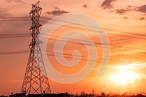 High voltage electric pylon and transmission lines with sunset sky and cityscape. Electricity pylons. High voltage grid tower.