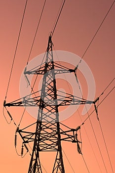 High voltage electric tower silhouette on bright orange background