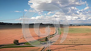 High voltage electric towers at sunny summer day. Transmission power lines in wheat field. Electrical equipment and high voltage p