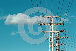 High voltage electric transmission towers and high voltage power lines over blue sky background