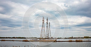 High voltage electric transmission towers in a lake, cludy sky