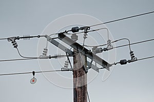 High voltage electrical power cables and insulators seen on wooden poles.