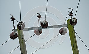 High voltage electrical power cables and insulators seen on wooden poles.