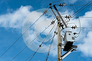 High voltage electrical power cables and insulators seen on wooden poles.