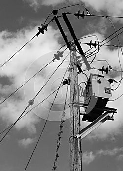 High voltage electrical power cables and transformer seen erected on a wooden pole.