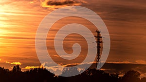 High voltage electrical tower at gold sunset background.