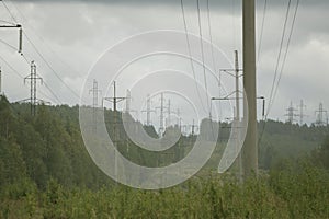 High voltage electrical transmission towers electricity pylons and power lines on green field