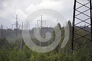 High voltage electrical transmission towers electricity pylons and power lines on green field