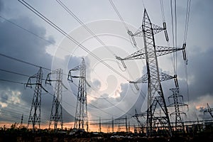 High-voltage electricity grid of power lines, with stormy clouds breaking apart at sunset. Electric transmission towers.