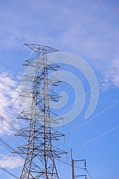 High voltage electricity pylon against blue sky background in low angle view and vertical frame