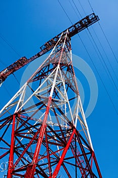High-voltage electricity pylon and power lines against blue sky