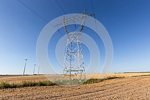 High voltage electricity tower and wind farm under blue sky