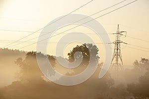 High voltage electricity transfer lines and pylon in a fog