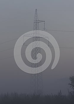 High voltage electricity transfer lines and pylon in a fog