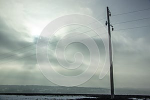 High voltage electricity transfer lines and pylon in a fog