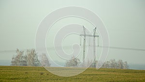 High voltage electricity transfer lines and pylon in a fog