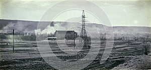 High-voltage line passing through the field in the background of the hills in the smoke. Black and white photo in retro style