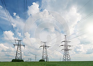 High voltage lines and power poles and green agricultural landscape during sunset