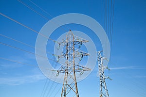 High voltage lines and power pylons against blue sky
