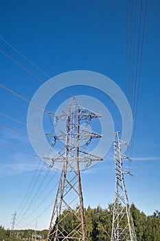 High voltage lines and power pylons against blue sky