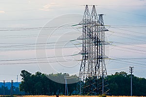 High voltage lines and power pylons in a flat and green agricultural landscape