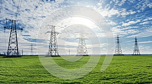 High voltage lines and power pylons and a green agricultural landscape on a sunny day