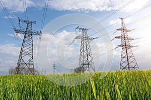 High voltage lines and power pylons and a green agricultural landscape on a sunny day