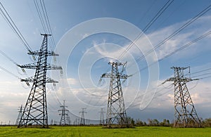 High voltage lines and power pylons and a green agricultural landscape on a sunny day