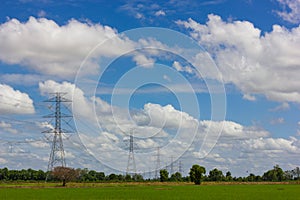 High voltage pole with green fields.