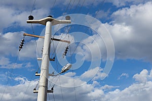 High-voltage pole with insulators and wires against blue sky.